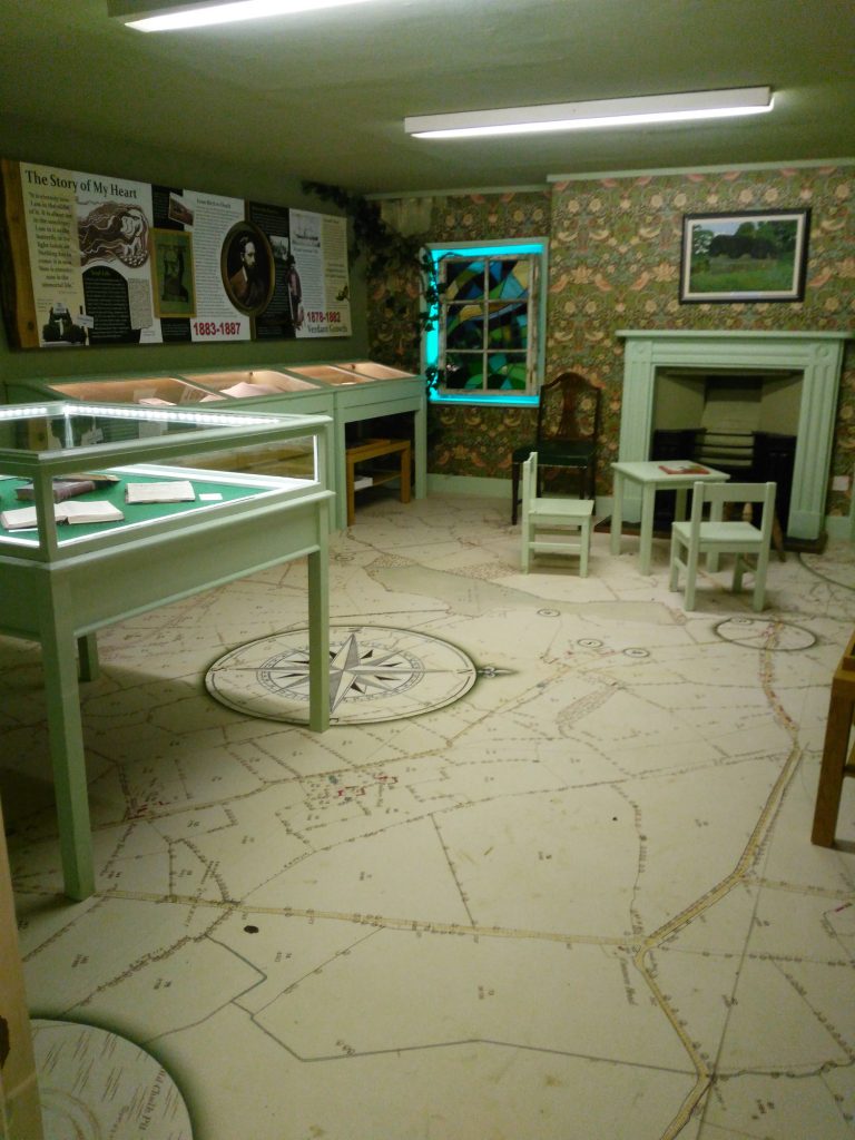The only 'proper' museum room, full of exhibits, floors are a map of the local area, with a weird faux stained glass window at one end.